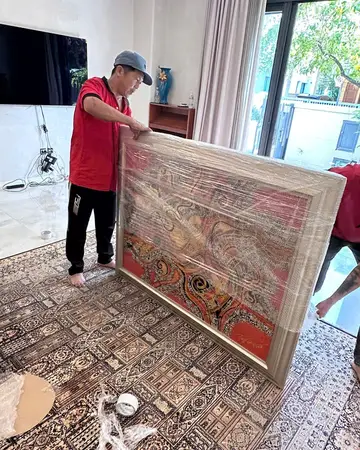 Nhân viên Thành Hưng bọc tranh khổ lớn trước khi đưa ra xe